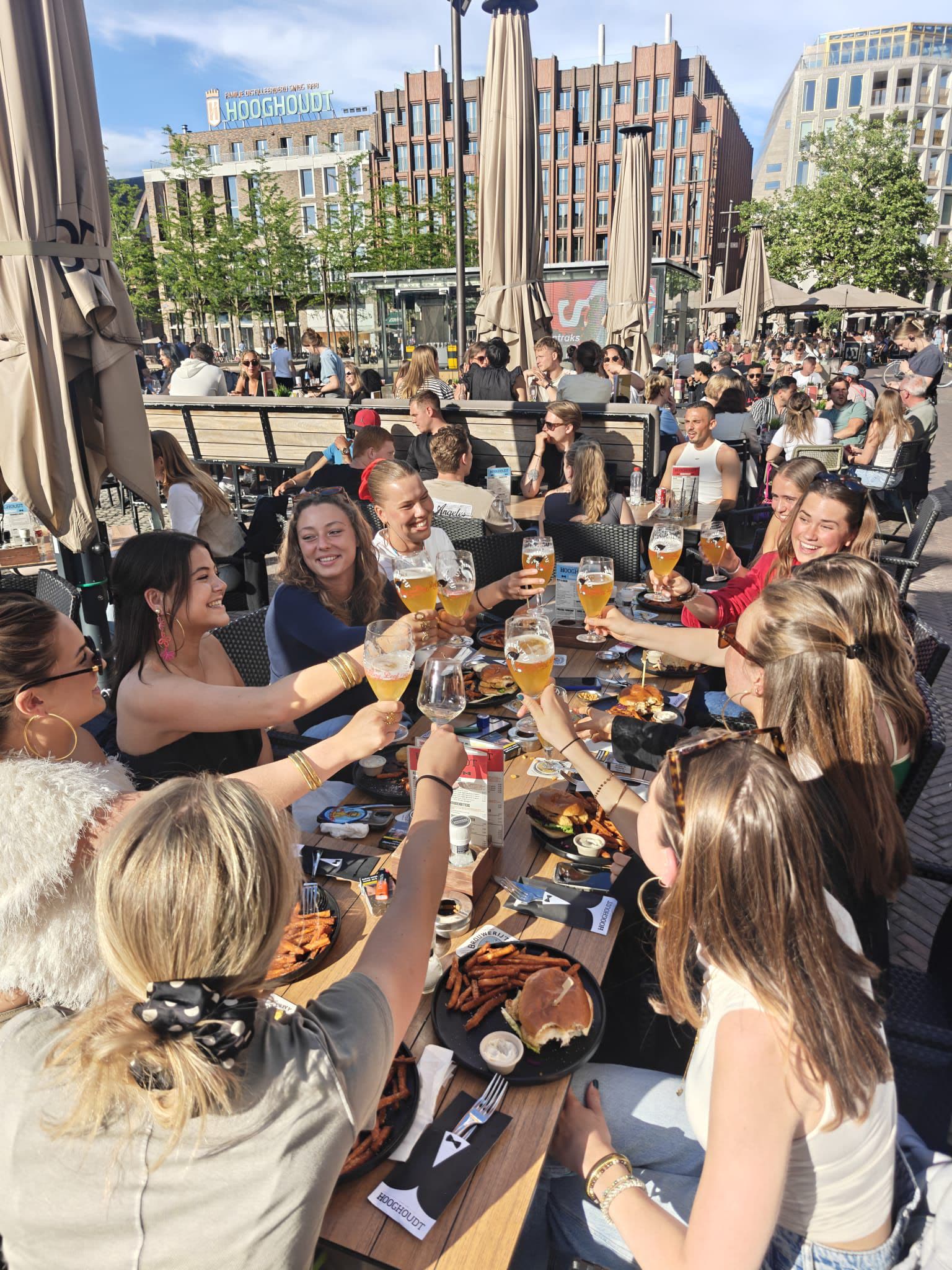 Vriendinnen proosten samen op het terras van Café Hooghoudt.